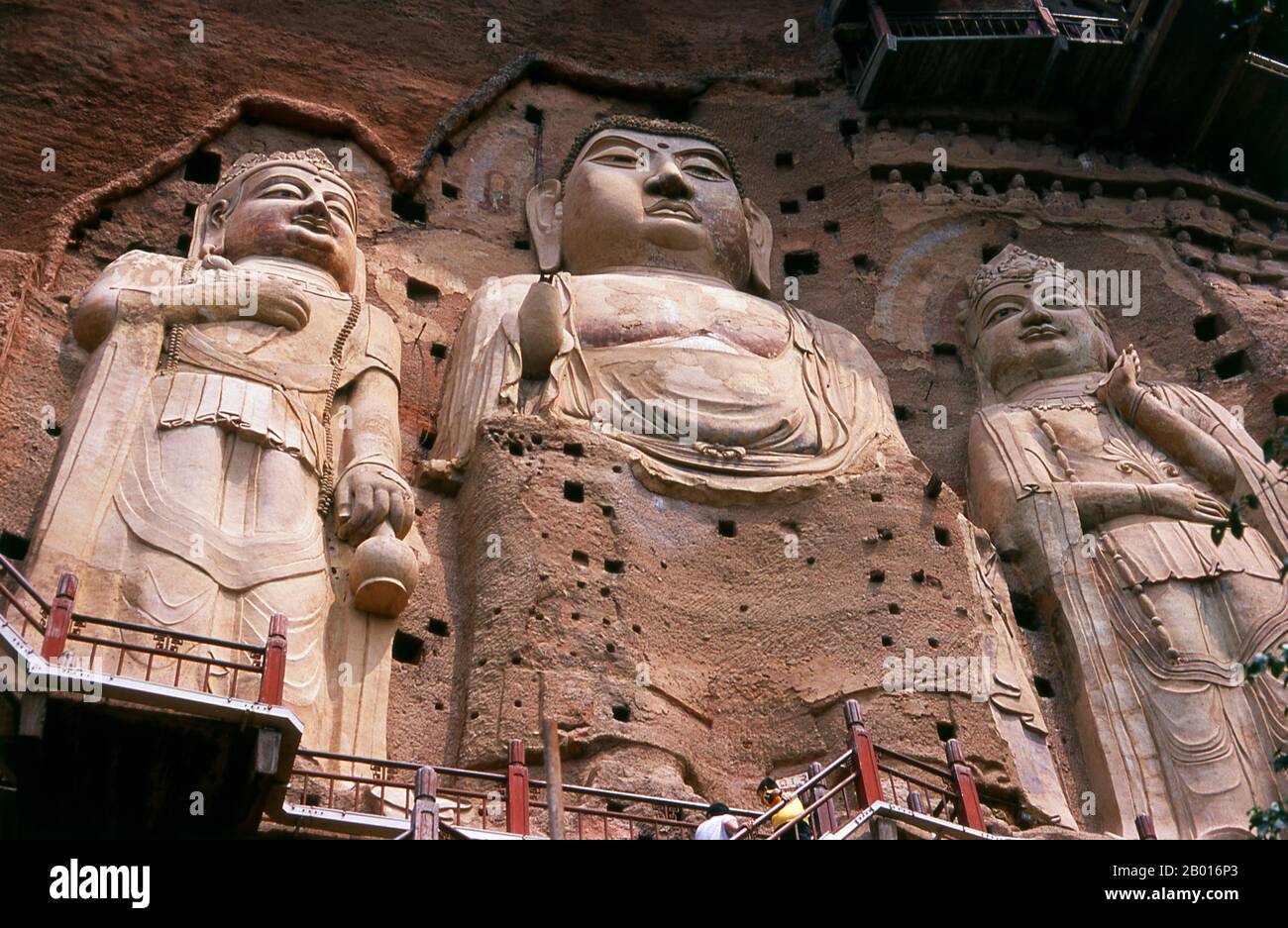 China: Buddhas first carved during the Sui Dynasty (581 - 618 CE), Maiji Shan Grottoes, Tianshui, Gansu Province.  Maijishan Shiku (Maiji Shan Grottoes) are one of China’s four most important Buddhist temple groups (the others being Datong, Luoyang, and the Mogao Caves at Dunhuang).  Starting from the Northern Wei (386-535) and Northern Zhou (557-81) Dynasties, Buddhists cut caves into the sides of a red outcrop rising from the surrounding foliage-covered hills. Figures of the Buddha, of bodhisattvas and disciples were carved in harder rock brought from elsewhere, and installed in the caves. Stock Photo