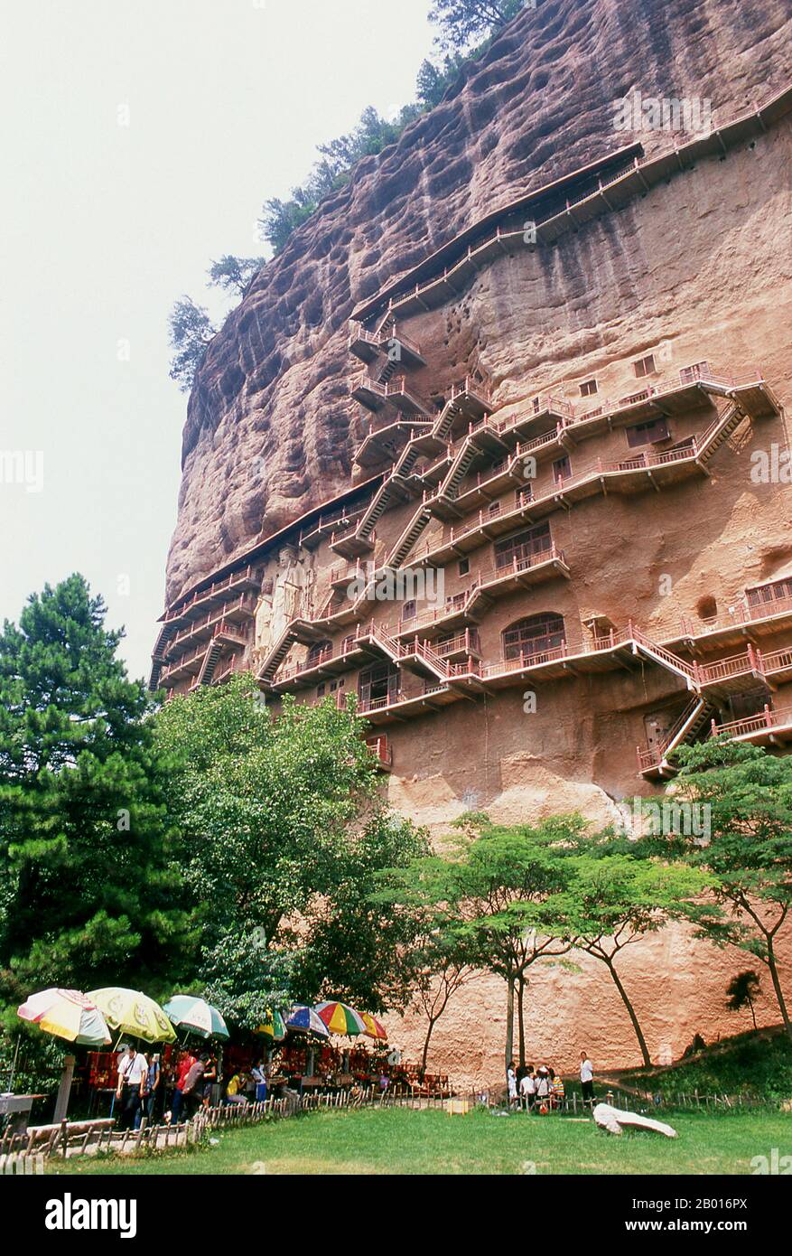 China: Staircases crisscross the Maiji Shan Grottoes, Tianshui, Gansu Province.  Maijishan Shiku (Maiji Shan Grottoes) are one of China’s four most important Buddhist temple groups (the others being Datong, Luoyang, and the Mogao Caves at Dunhuang).  Starting from the Northern Wei (386-535) and Northern Zhou (557-81) Dynasties, Buddhists cut caves into the sides of a red outcrop rising from the surrounding foliage-covered hills. Figures of the Buddha, of bodhisattvas and disciples were carved in harder rock brought from elsewhere, and installed in the caves. Stock Photo