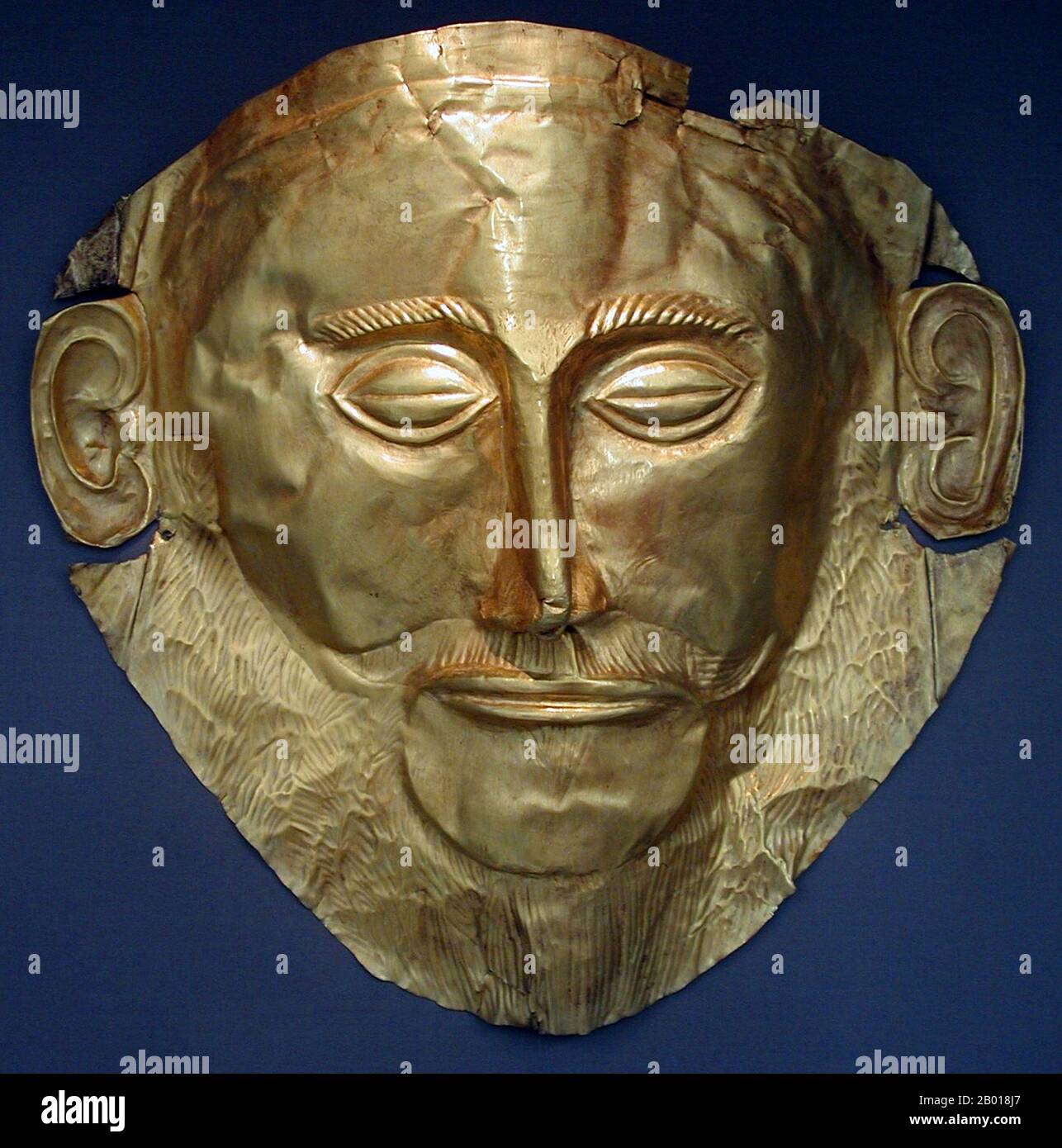 Greece: Golden funeral mask also known as the Agamemnon Mask. Found in Tomb V in Mycenae by Heinrich Schliemann in 1876, 16th century BCE. Photo by DieBuche (CC BY-SA 3.0 License).  In Greek mythology, Agamemnon was the son of King Atreus of Mycenae and Queen Aerope; the brother of Menelaus and the husband of Clytemnestra; mythical legends make him the king of Mycenae or Argos, thought to be different names for the same area. When Helen, the wife of Menelaus, was abducted by Paris of Troy, Agamemnon was the commander of the Greeks in the ensuing Trojan War. Stock Photo