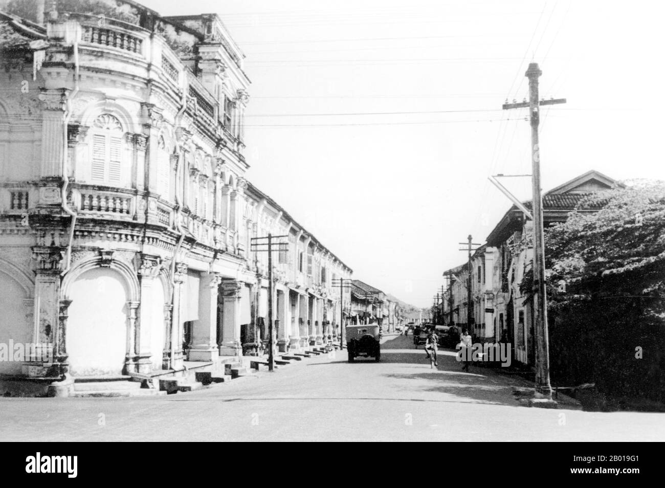 Thailand: Sino-Portuguese shophouses along Thanon Yaowarat (Yaowarat Road), Phuket, 1957.  Phuket, formerly known as Talang and, in Western sources, Junk Ceylon (a corruption of the Malay Tanjung Salang, i.e. 'Cape Salang'), is one of the southern provinces (changwat) of Thailand. Neighbouring provinces are (from north clockwise) Phang Nga and Krabi, but as Phuket is an island there are no land boundaries.  Phuket, which is approximately the size of Singapore, is Thailand’s largest island. The island is connected to mainland Thailand by two bridges. Stock Photo