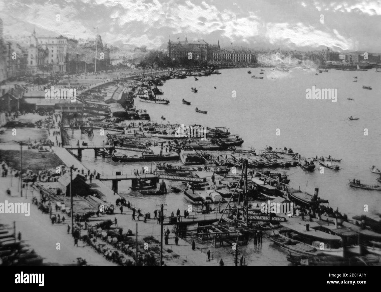 China: A long view of the Shanghai Bund (Waitan), c. 1925.  The Bund (Chinese: Wàitān) is an area of Huangpu District in central Shanghai. The area centres on a section of Zhongshan Road (East-1 Zhongshan Road) within the former Shanghai International Settlement, which runs along the western bank of the Huangpu River, facing Pudong, in the eastern part of Huangpu District. The Bund usually refers to the buildings and wharves on this section of the road, as well as some adjacent areas. Stock Photo