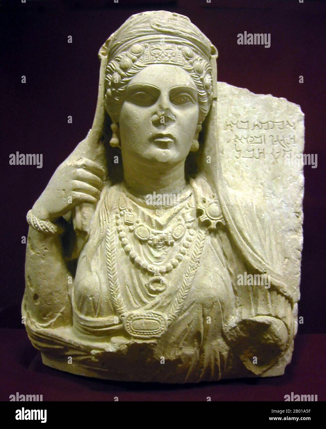 Syria: Funerary bust of a noblewoman of Palmyra, 2nd century CE. Photo by PHGCOM (CC BY-SA 3.0 License).  Funerary bust of Aqmat, daughter of Hagagu, descendant of Zebida, descendant of Ma'an, with Palmyrenian inscription. Stock Photo