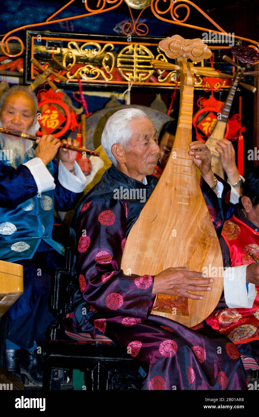 China: A man plucks a pipa or Chinese lute, the Naxi (Nakhi) Folk Orchestra, Naxi Orchestra Hall, Lijiang Old Town, Yunnan Province.  Naxi music is 500 years old, and with its mixture of literary lyrics, poetic topics, and musical styles from the Tang, Song, and Yuan dynasties, as well as some Tibetan influences, it has developed its own unique style and traits. There are three main styles: Baisha, Dongjing, and Huangjing, all using traditional Chinese instruments.  The Naxi or Nakhi are an ethnic group inhabiting the foothills of the Himalayas in the northwestern part of Yunnan Province. Stock Photo