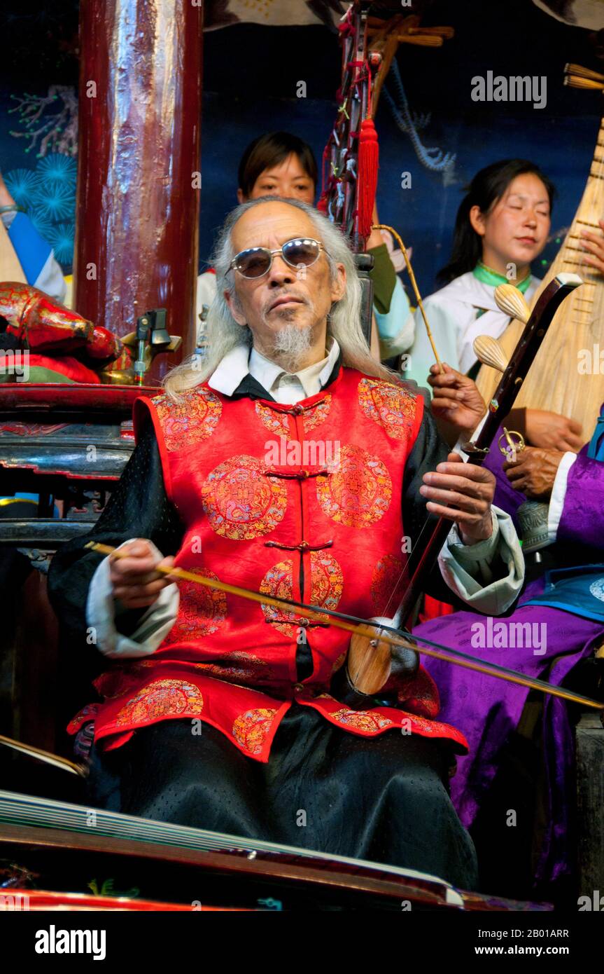 China: A man plays a banhu, the Naxi (Nakhi) Folk Orchestra, Naxi Orchestra Hall, Lijiang Old Town, Yunnan Province.  Naxi music is 500 years old, and with its mixture of literary lyrics, poetic topics, and musical styles from the Tang, Song, and Yuan dynasties, as well as some Tibetan influences, it has developed its own unique style and traits. There are three main styles: Baisha, Dongjing, and Huangjing, all using traditional Chinese instruments.  The Naxi or Nakhi are an ethnic group inhabiting the foothills of the Himalayas in the northwestern part of Yunnan Province. Stock Photo