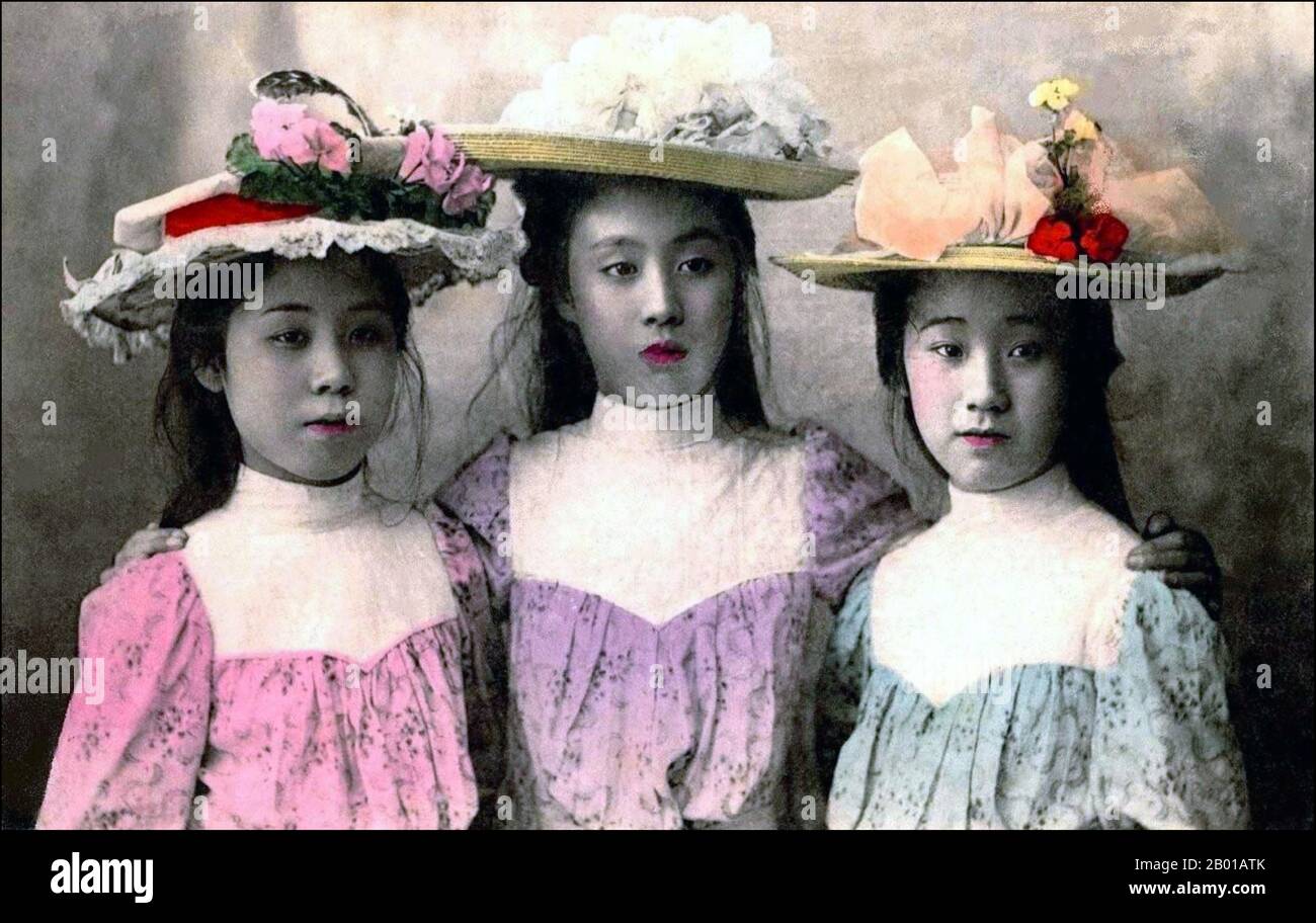 Japan: Three young women dressed in Western fashion. Hand-tinted photograph by Enami Nobukuni (1859-1929), c. 1895.  T. Enami was the trade name of a celebrated Meiji period photographer. The T. of his trade name is thought to have stood for Toshi, though he never spelled it out on any personal or business document.  Born in Edo (now Tokyo) during the Bakumatsu era, Enami was first a student of, and then an assistant to the well known photographer and collotypist, Ogawa Kazumasa. Enami relocated to Yokohama, and opened a studio on Benten-dōri (Benten Street) in 1892. Stock Photo