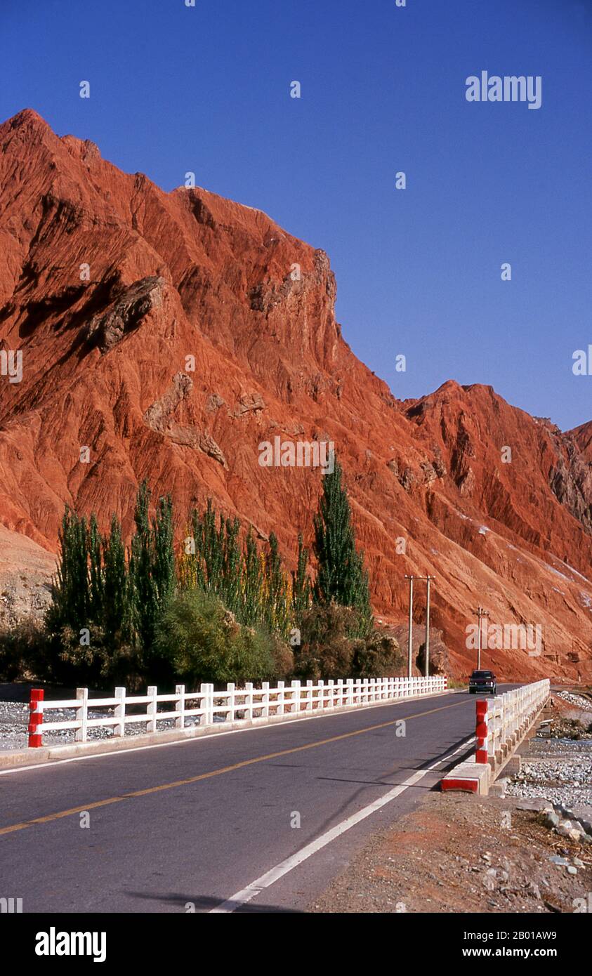 China: The red mountains of the Ghez River (Ghez Darya) canyon, Karakoram Highway.  The Zhongba Gonglu or Karakoram Highway is an engineering marvel that was opened in 1986 and remains the highest paved road in the world. It connects China and Pakistan across the Karakoram mountain range, through the Khunjerab Pass, at an altitude of 4,693 m/15,397 ft. Stock Photo