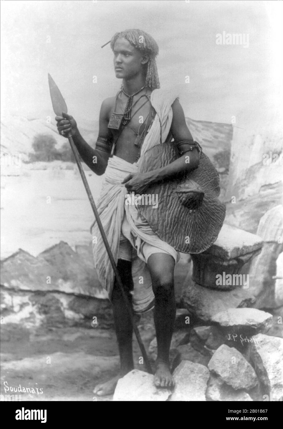 Sudan: A Sudanese warrior. Photo by Jean Pascal Sebah (1872 - 6 June 1947), c. 1920-1930.  The Republic of Sudan is a country in North Africa. It is bordered by Egypt to the north, the Red Sea to the northeast, Eritrea and Ethiopia to the east, South Sudan to the south, the Central African Republic to the southwest, Chad to the west and Libya to the northwest. The world's longest river, the Nile, divides the country between east and west sides. Stock Photo