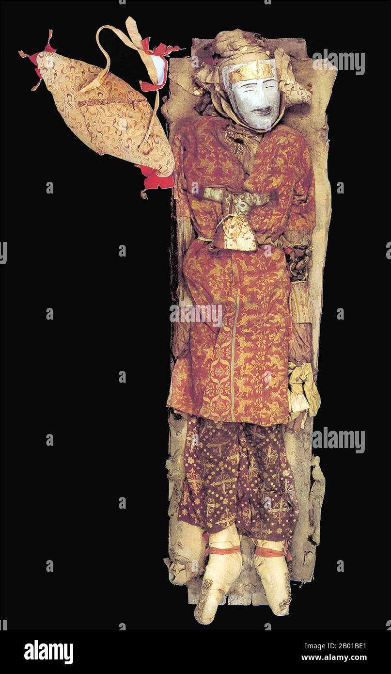 China: About two thousand years old, Yingpan man died at around thirty and was buried in elaborate clothing with a gold face mask, 3rd-4th century CE.  The best preserved of the corpses discovered at the cemetery at Zaghunluq in the Tarim Basin, is the 'Yingpan Man'. The two metres tall, 2,000 year old Caucasian mummy was discovered in 1995. His face was blond and bearded and was covered with a gold foil death mask; he also wore an elaborate golden embroidered red and maroon wool garments with images of fighting. His head rests on a pillow in the shape of a crowing cockerel. Stock Photo