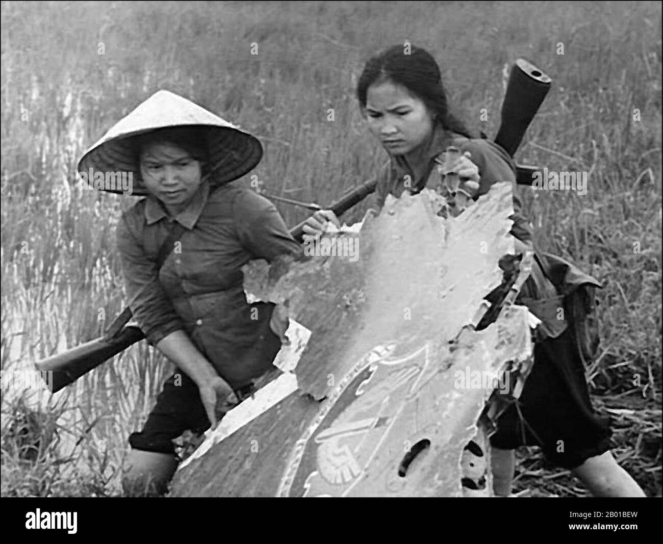 Vietnam: Two National Liberation Front (NLF,  Viet Cong) women fighters salvage wreckage from a downed USAF plane, c. 1968.  The Second Indochina War, known in America as the Vietnam War, was a Cold War era military conflict that occurred in Vietnam, Laos, and Cambodia from 1 November 1955 to the fall of Saigon on 30 April 1975. This war followed the First Indochina War and was fought between North Vietnam, supported by its communist allies, and the government of South Vietnam, supported by the U.S. and other anti-communist nations. Stock Photo