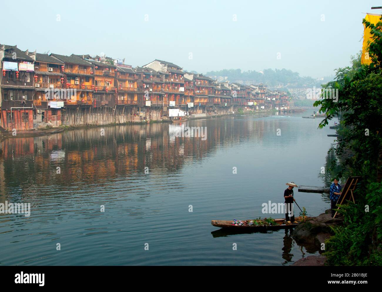 China: Early morning on Fenghuang's misty Tuo River, Fenghuang, Hunan Province.  Fenghuang is Chinese for Phoenix and refers to the mythical sacred firebird that can be found in the mythologies of the Persians, Greeks, Romans, Egyptians, Chinese, and (according to Sanchuniathon) the Phoenicians.  Legend suggests that two phoenixes on discovering the town hovered overhead for some considerable time before reluctantly flying away.  Fenghuang town is a well-preserved ancient town supposedly dating back to 248 BC. It is home to the Miao and Tujia minorities. Stock Photo