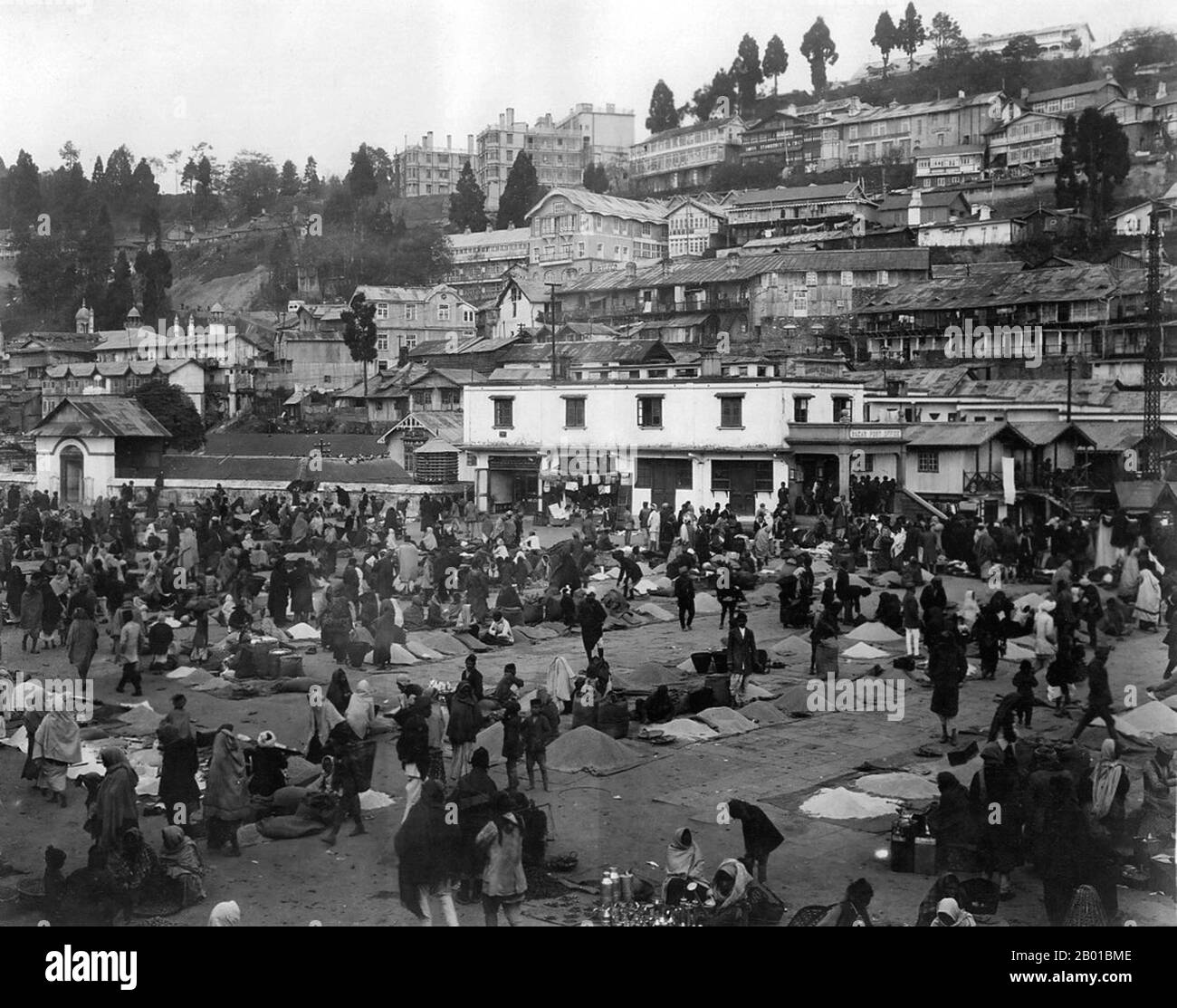 India/Sikkim: The central marketplace in Gangtok, capital of Sikkim, c. 1935.  Gangtok is the capital and largest town of the Indian state of Sikkim. It is located in the Shivalik Hills of the eastern Himalayan range, at an altitude of 1,437 metres (4,715 ft). The town has a population of thirty thousand belonging to different ethnicities including Nepalis, Lepchas and Bhutia.  Gangtok rose to prominence as a popular Buddhist pilgrimage site after the construction of the Enchey Monastery in 1840. In 1894, the ruling Sikkimese Chogyal, Thutob Namgyal, transferred the capital to Gangtok. Stock Photo