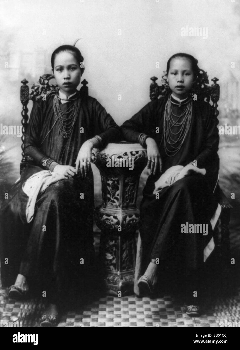 Vietnam: Two young Viet (Kinh) women of Saigon, c. 1905.  Ho Chi Minh City (Vietnamese: Thành phố Hồ Chí Minh, better known as Saigon (Vietnamese: Sài Gòn) is the largest city in Vietnam. It was once known as Prey Nokor, an important Khmer sea port prior to annexation by the Vietnamese in the 17th century.  Under the name Saigon, it was the capital of the French colony of Cochin-china and later of the independent state of South Vietnam from 1955 to 1975. In 1976, Saigon merged with the surrounding Gia Định Province and was officially renamed Hồ Chí Minh City after Hồ Chí Minh. Stock Photo