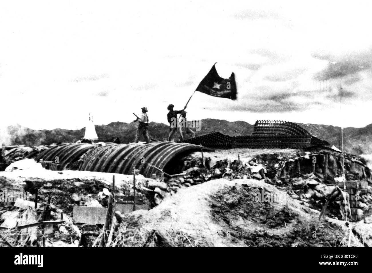 Vietnam: Victorious Viet Minh troops wave a Vietnamese flag over captured French positions at Dien Bien Phu, 1954.  The important Battle of Dien Bien Phu was fought between the Việt Minh (led by General Vo Nguyen Giap), and the French Union (led by General Henri Navarre, successor to General Raoul Salan). The siege of the French garrison lasted fifty-seven days, from 5:30PM on March 13 to 5:30PM on May 7, 1954.  The southern outpost or fire base of the camp, Isabelle, did not follow the cease-fire order and fought until the next day at 01:00 AM. Stock Photo