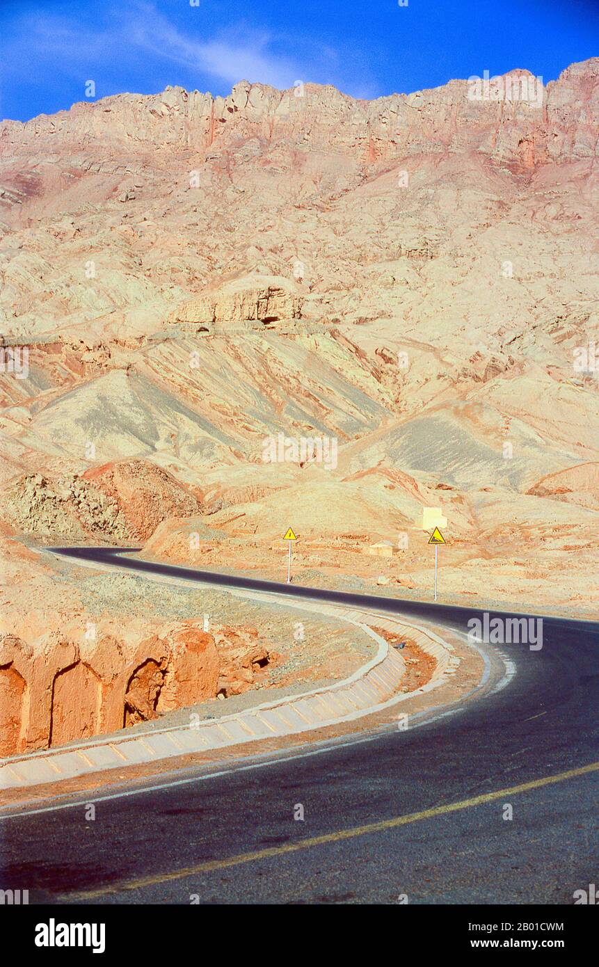 China: Road running next to the village of Tuyoq near Turpan, Xinjiang Province.  Tuyoq or Tuyugou is an ancient oasis-village in the Taklamakan desert, 70 km east of Turpan in a lush valley cutting into the Flaming Mountains, with a well preserved Uyghur orientation. It is famous for its seedless grapes and a number of ancient Buddhist meditation caves nearby containing frescos, the best known being the Bezeklik Thousand Buddha Caves. Stock Photo