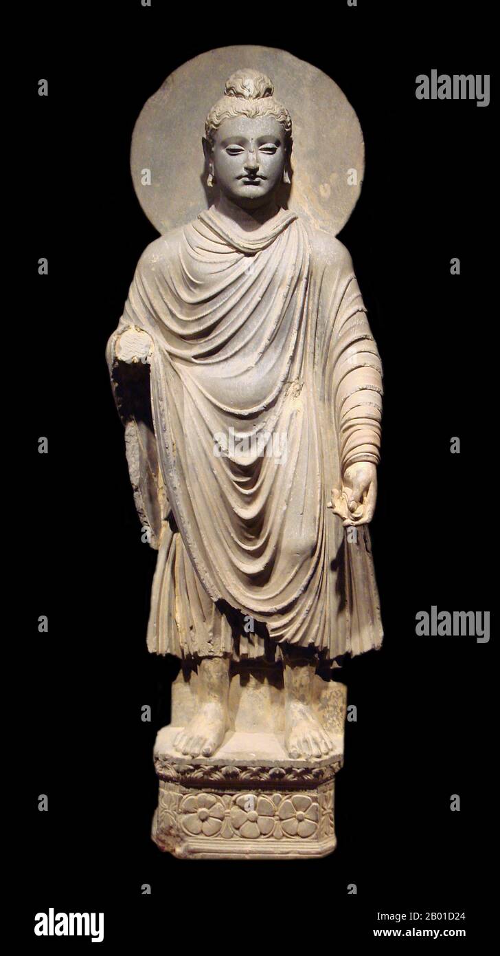 Pakistan/Afghanistan: Standing image of the Buddha, Gandhara Kingdom, 1st-2nd century CE.  Gandhāra is noted for the distinctive Gandhāra style of Buddhist art, which developed out of a merger of Greek, Syrian, Persian and Indian artistic influence. This development began during the Parthian Period (50 BCE - 75 CE). Gandhāran style flourished and achieved its peak during the Kushan period, from the 1st to the 5th century. It declined and suffered destruction after invasion of the White Huns in the 5th century. Stock Photo