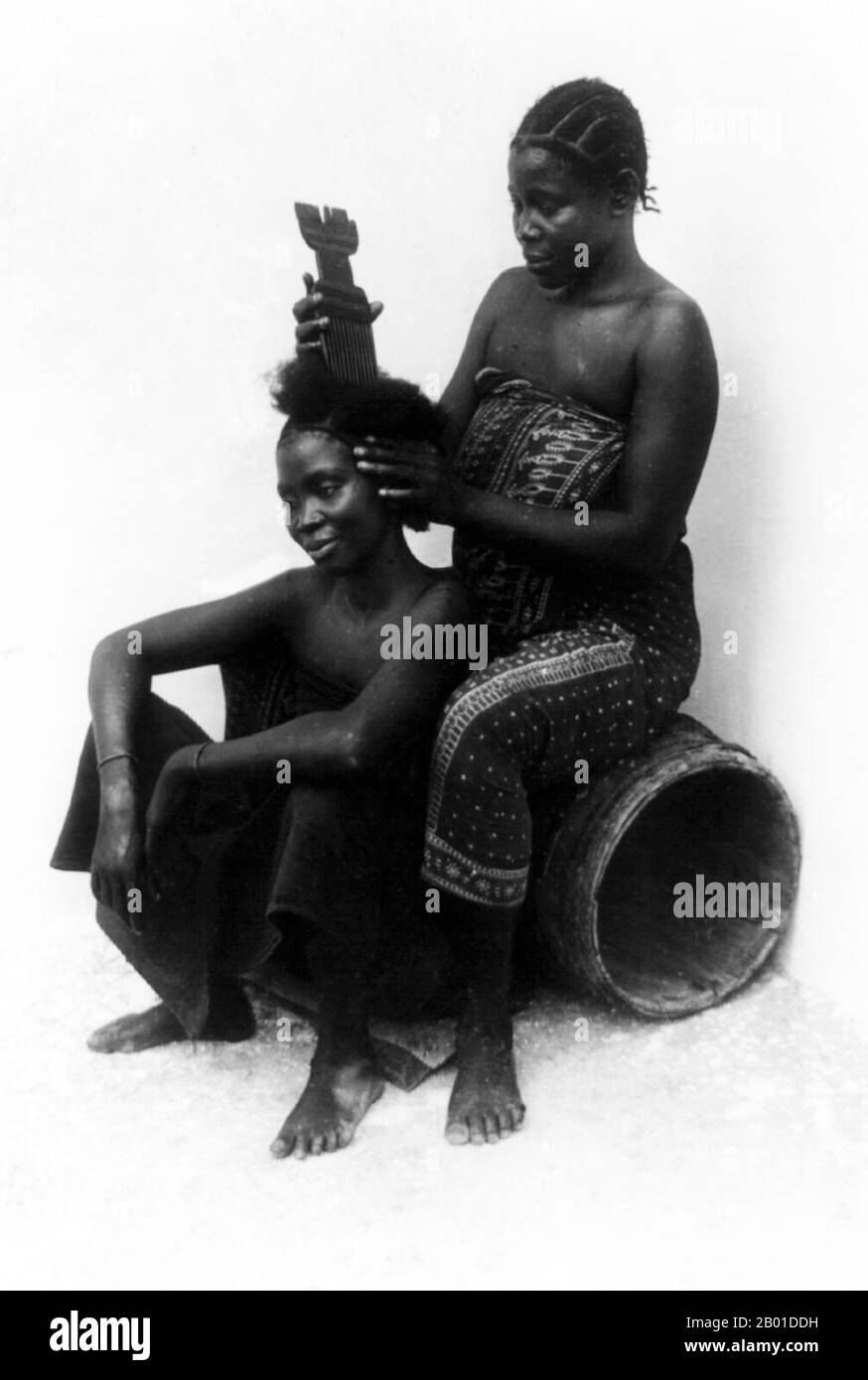 Tanzania: Swahili hair stylist at work, Zanzibar, British East Africa, c. 1890s.   Both women are wearing kanga, or printed cotton wrap-around skirts characteristic of the area.  The Swahili people are a Bantu ethnic group and culture found in East Africa, mainly in the coastal regions and the islands of Kenya, Tanzania and northern Mozambique. The name Swahili is derived from the Arabic word Sawahil, meaning 'coastal dwellers', and they speak the Swahili language.  The Swahili are original Bantu inhabitants on the coast of East Africa, in Kenya, Tanzania and Mozambique. Stock Photo
