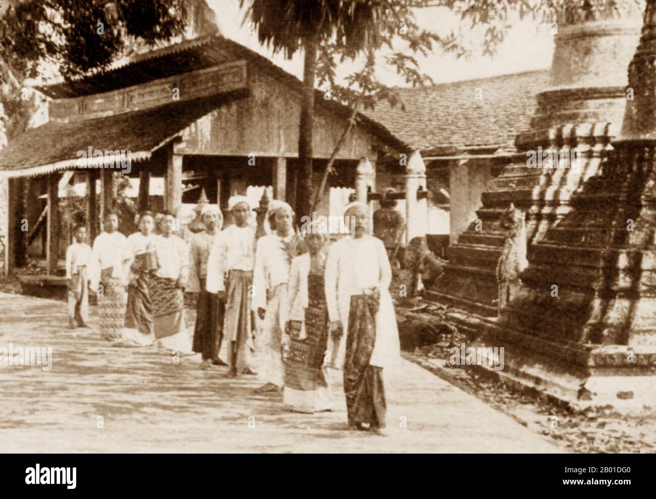 Burma: A high-ranking Burmese gentleman, followed by his family, leaves a Buddhist temple, c. 1892-1896.  Legend attributes the first Buddhist doctrine in Burma to 228 BCE when Sonna and Uttara, two ambassadors of the Emperor Ashoka the Great of India, came to the country with sacred texts. However, the golden era of Buddhism truly began in the 11th century after King Anawrahta of Pagan (Bagan) was converted to Theravada Buddhism. Today, 89% of the population of Burma is Theravada Buddhist. Stock Photo