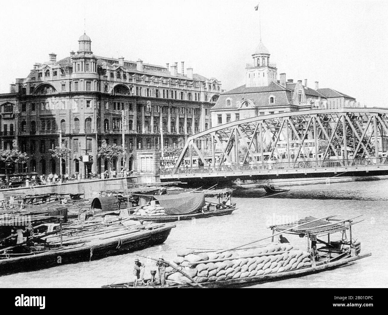 China: Shanghai's Waibaidu Bridge, located at the junction of the Huangpu River and Suzhou Creek, c. 1930s.  The Waibaidu Bridge (Chinese: 外白渡桥; pinyin: Wàibáidù Qiáo), called The Garden Bridge in English, is the first all-steel bridge, and the only surviving example of a camelback truss bridge, in China.  The fourth foreign bridge built at its location since 1856, in the downstream of the estuary of the Suzhou Creek, near its confluence with the Huangpu River and adjacent to the Bund in central Shanghai, and connecting the Huangpu and Hongkou districts, the present bridge was opened in 1908. Stock Photo