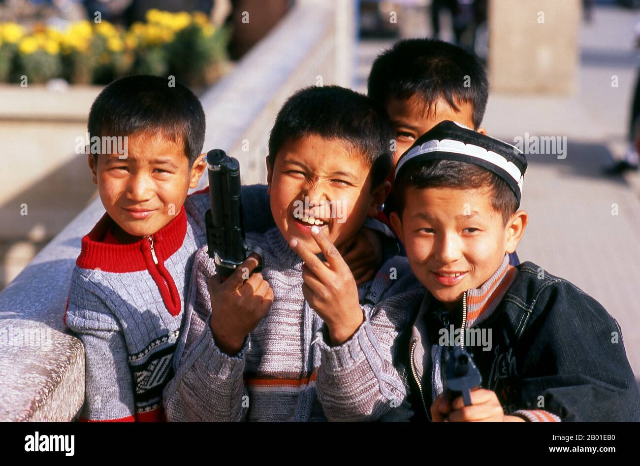 China: Uighur boys with their toy guns, Kuqa, Xinjiang Province.  The ancient oasis town of Kuqa (Kuche), though now overshadowed by Korla to the east and Aksu to the west, was once a key stop on the Northern Silk Road. It first came under Han Chinese control when it was conquered, in 91 CE, by the indomitable General Ban Chao.  By the 4th century it had emerged as an important centre of Tocharian civilisation sitting astride not just the Northern Silk Road, but also lesser routes to Dzungaria in the north and Khotan in the south. The celebrated Buddhist monk Kumarajiva was born here. Stock Photo