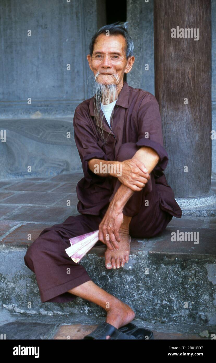 Vietnam: Portrait of an old man, Van Mieu (Temple of Literature), Hanoi.  The Temple of Literature or Van Mieu is one of Vietnam’s foremost cultural treasures. Founded in 1070 by King Ly Thanh Tong of the Early Ly Dynasty, the temple was originally dedicated both to Confucius and to Chu Cong, a member of the Chinese royal family credited with originating many of the teachings that Confucius developed five hundred years later. The site was selected by Ly Dynasty geomancers to stand in harmony with the Taoist Bich Cau temple and the Buddhist One Pillar Pagoda. Stock Photo