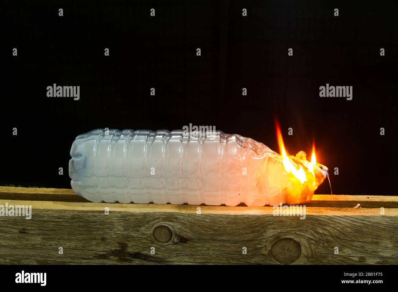 inflamed plastic bottle filled with toxic smoke that burns and burns out leaving toxic smoke on a black background Stock Photo