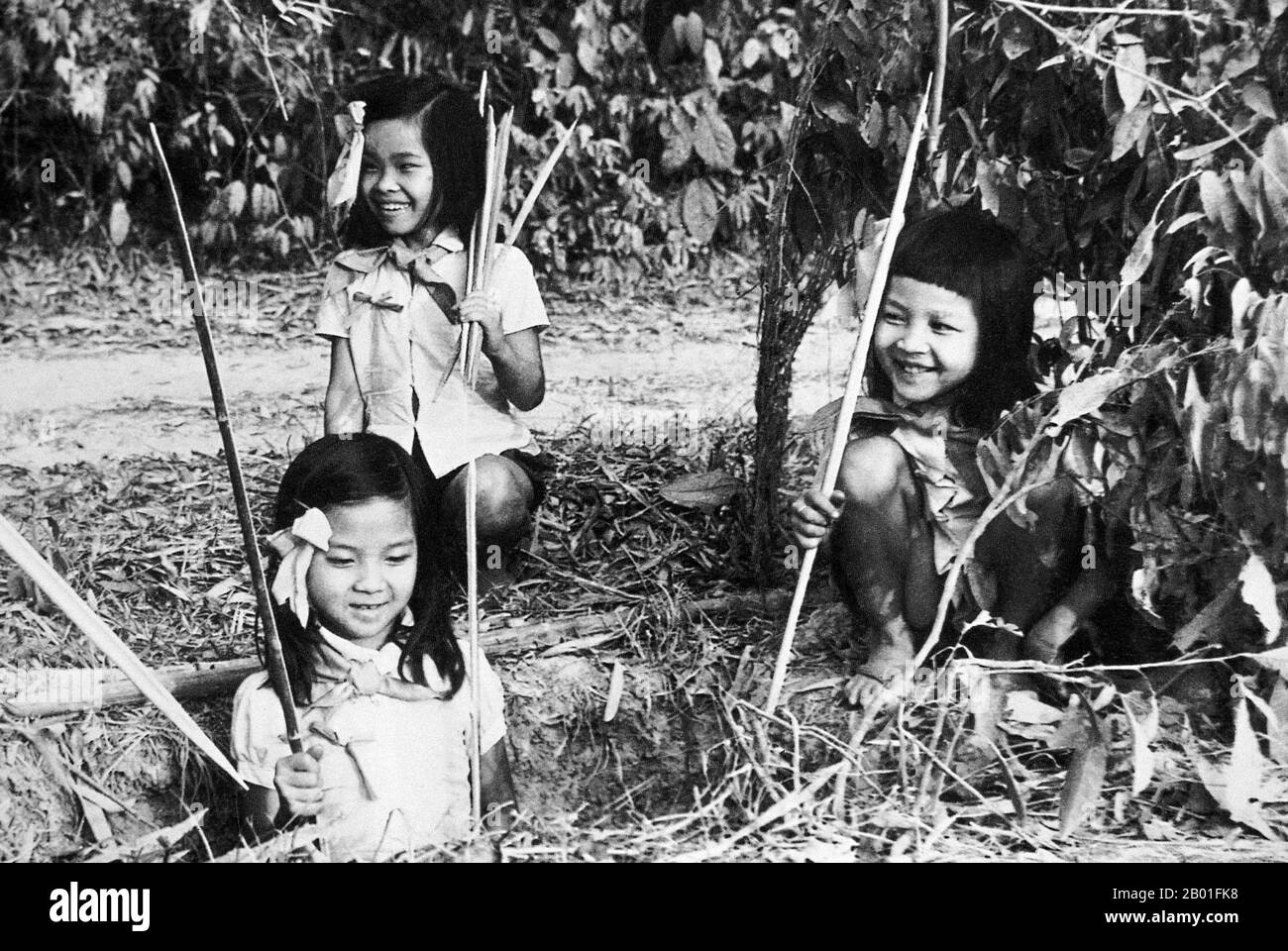 Vietnam: Vietnamese children making panji bamboo traps at Cu Chi, 1968.  The Second Indochina War, known in America as the Vietnam War, was a Cold War era military conflict that occurred in Vietnam, Laos, and Cambodia from 1 November 1955 to the fall of Saigon on 30 April 1975. This war followed the First Indochina War and was fought between North Vietnam, supported by its communist allies, and the government of South Vietnam, supported by the U.S. and other anti-communist nations. The U.S. government viewed involvement in the war as a way to prevent a communist takeover of South Vietnam. Stock Photo