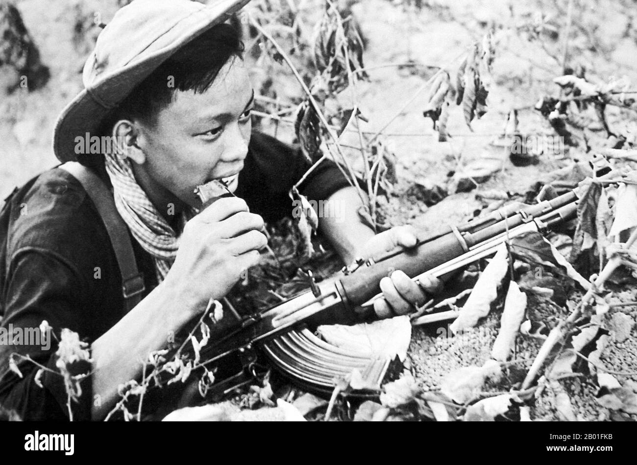 Vietnam: NLF (Viet Cong) soldier with AK47 assault rifle near Saigon, 1968.  The Second Indochina War, known in America as the Vietnam War, was a Cold War era military conflict that occurred in Vietnam, Laos, and Cambodia from 1 November 1955 to the fall of Saigon on 30 April 1975. This war followed the First Indochina War and was fought between North Vietnam, supported by its communist allies, and the government of South Vietnam, supported by the U.S. and other anti-communist nations. The U.S. government viewed involvement in the war as a way to prevent a communist takeover of South Vietnam. Stock Photo