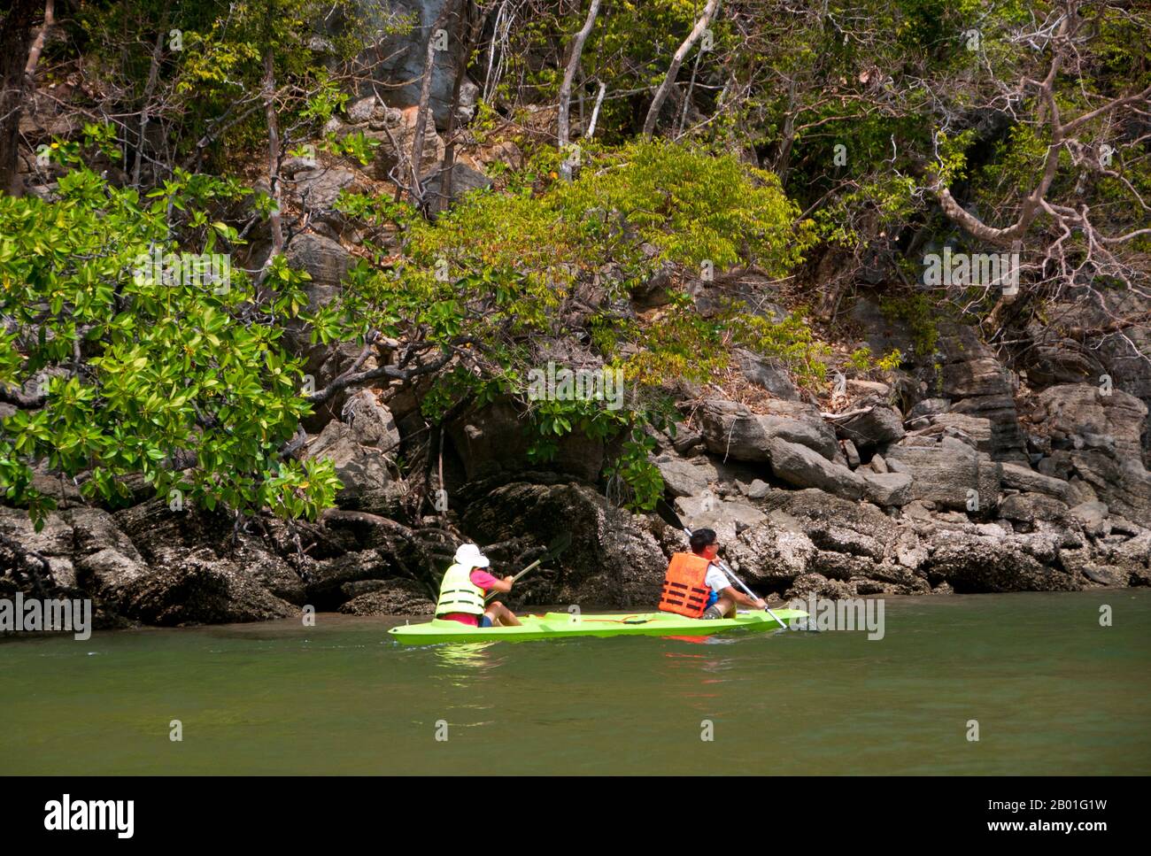 Thailand: Kayakers near the To-Bu (Toe-Boo) cliff area, Ko Tarutao, Ko Tarutao Marine National Park.  Ko Tarutao Marine National Park consists of 51 islands in two main groups scattered across the Andaman Sea in southernmost Thailand. Just seven of the islands are of any size, including Ko Tarutao in the east, and Ko Adang-Ko Rawi to the west. Just 5 miles (8 km) to the south lies the marine frontier with Malaysia’s celebrated Langkawi Archipelago.  Tarutao is world-famous for its pristine diving sites, rich marine life and outstanding natural beauty. Stock Photo