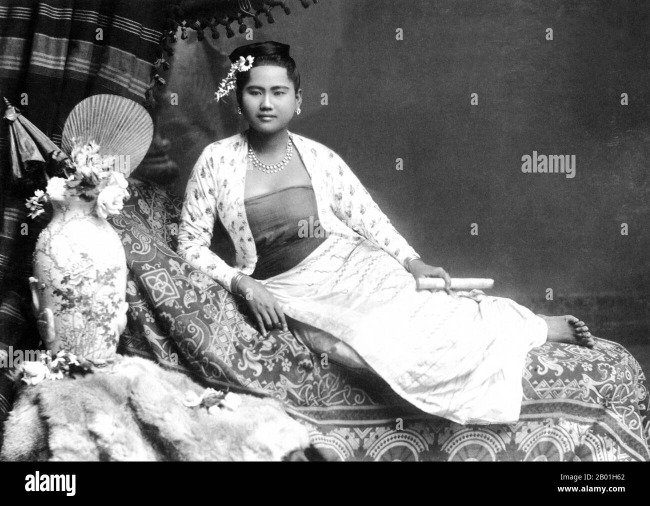 Burma/Myanmar: Studio portrait by Philip Adolphe Klier (1845 - 27 March 1911) of a young Burman woman with a cheroot, probably Rangoon/Yangon, 1895.  Philip Adolphe Klier was a German photographer best known for his photographs of colonial Burma / Myanmar. By 1871 he was a professional photographer in Moulmein, Burma. His business included work as an optician, watchmaker and jeweller as well running the firm known as Murken & Klier.  Around 1880 Klier moved to Rangoon, Burma‘s largest city, which had become the centre of Indo-British power since the conquest of the Irrawaddy Delta in 1852. Stock Photo