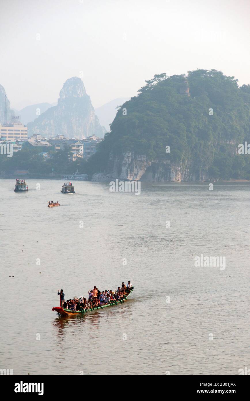China: Boats on the Li River, Guilin, Guangxi Province.  Guilin's Dragon Boat Festival is held on the fifth day of the fifth month (May) of the Chinese lunar calendar every 3 years. The festival was originally held in memory of the great Chinese poet, Quyuan.  The name Guilin means ‘Cassia Woods’ and is named after the osmanthus (cassia) blossoms that bloom throughout the autumn period.  Guilin is the scene of China’s most famous landscapes, inspiring thousands of paintings over many centuries. Stock Photo