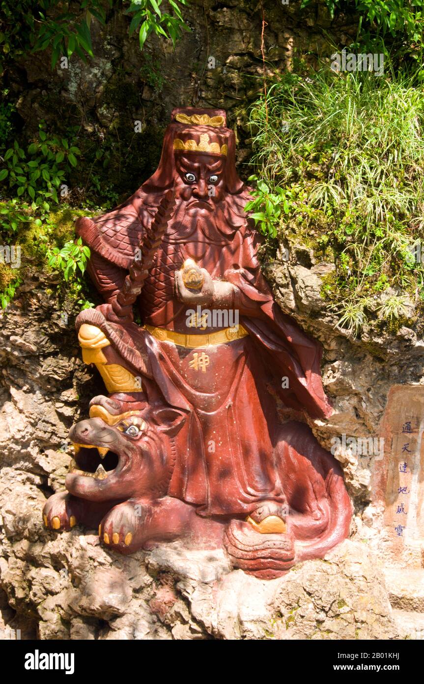 China: Guardian figure at Long Men (Dragon Gate), Xishan, near Kunming, Yunnan Province.  Lying 15 km west of Kunming City, the Dragon Gate (Long Men) in the Western Hills is close to the west shore of Dianchi Lake. It consists of the Sanqing Temple Complex and the Dragon Gate Grotto Complex.  Dragon Gate is over 2,300 metres, 300 metres higher than the water surface of Dianchi Lake.  Western Hills Forest Reserve lies in the Biji Mountain chain to the west of Kunming, China. It is visible from the eastern or northern banks of Dianchi Lake. Stock Photo