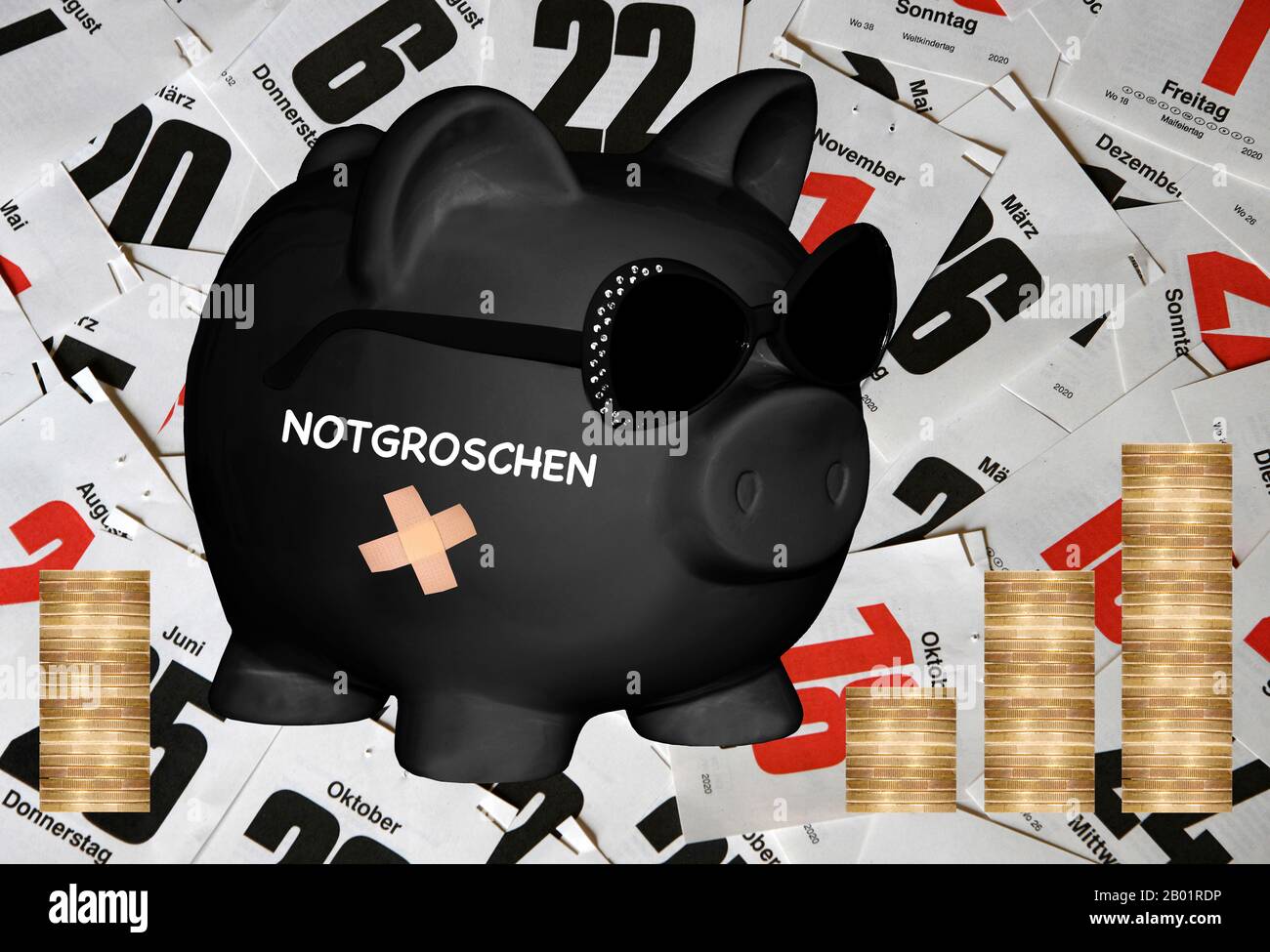 , black piggy bank with sunglasses and lettering Notgroschen, nest egg, calendar sheets and coin piles in background, composing Stock Photo