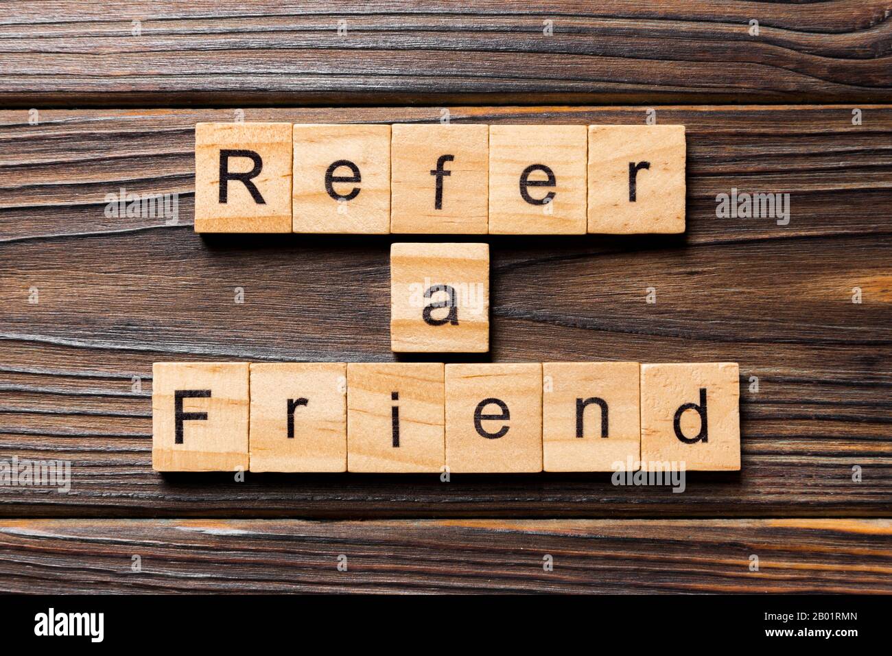 refer a friend word written on wood block. refer a friend text on table