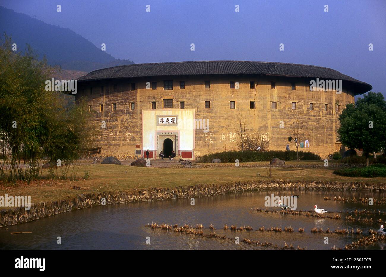 China: Zhenchang Lou Hakka Tower near Hukeng, Yongding County, Fujian Province.  The Hakka (kejia in Mandarin; literally 'guest people') are Han Chinese who speak the Hakka language. Their distinctive earthen houses or tulou can be found in the borderland counties where Guangdong, Jiangxi and Fujian provinces meet.  Communal entities, tulou are fortified against marauding bandits and generally made of compacted earth, bamboo, wood and stone. They contain many rooms on several storeys, so that several families can live together. Stock Photo