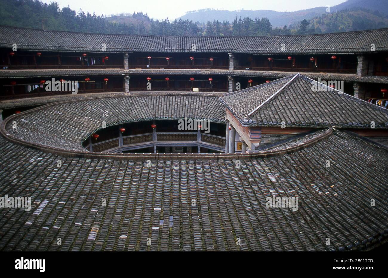 China: The inner courtyard at Zhenchang Lou Hakka Tower near Hukeng, Yongding County, Fujian Province.  The Hakka (Kejia in Mandarin; literally 'guest people') are Han Chinese who speak the Hakka language. Their distinctive earthen houses or tulou can be found in the borderland counties where Guangdong, Jiangxi and Fujian provinces meet.  Communal entities, tulou are fortified against marauding bandits and generally made of compacted earth, bamboo, wood and stone. They contain many rooms on several storeys, so that several families can live together. Stock Photo