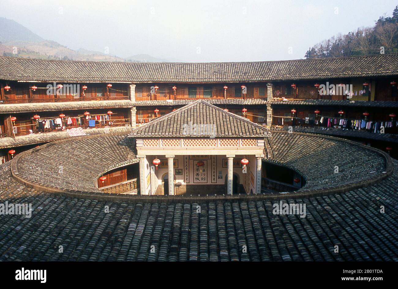 China: The inner courtyard at Zhenchang Lou Hakka Tower near Hukeng, Yongding County, Fujian Province.  The Hakka (Kejia in Mandarin; literally 'guest people') are Han Chinese who speak the Hakka language. Their distinctive earthen houses or tulou can be found in the borderland counties where Guangdong, Jiangxi and Fujian provinces meet.  Communal entities, tulou are fortified against marauding bandits and generally made of compacted earth, bamboo, wood and stone. They contain many rooms on several storeys, so that several families can live together. Stock Photo