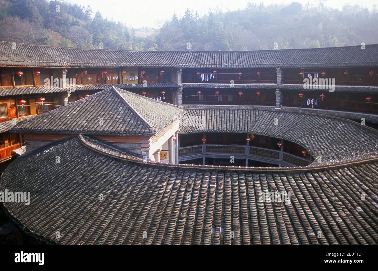 China: The inner courtyard at Zhenchang Lou Hakka Tower near Hukeng, Yongding County, Fujian Province.  The Hakka (Kejia in Mandarin; literally 'guest people') are Han Chinese who speak the Hakka language. Their distinctive earthen houses or tulou can be found in the borderland counties where Guangdong, Jiangxi and Fujian provinces meet.  Communal entities, tulou are fortified against marauding bandits and generally made of compacted earth, bamboo, wood and stone. They contain many rooms on several storeys, so that several families can live together. Stock Photo