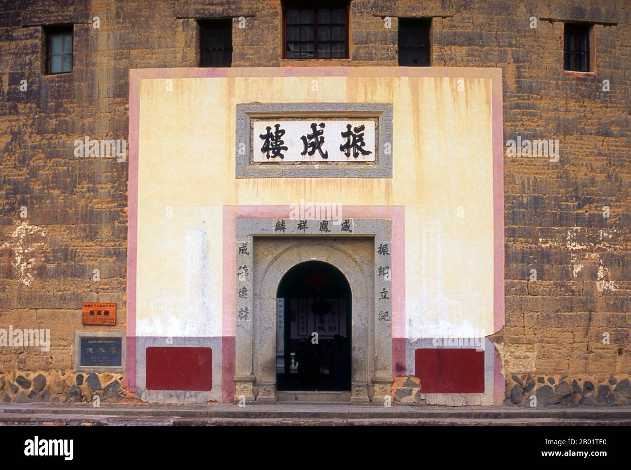 China: The only entrance into the Zhenchang Lou Hakka Tower near Hukeng, Yongding County, Fujian Province.  The Hakka (Kejia in Mandarin; literally 'guest people') are Han Chinese who speak the Hakka language. Their distinctive earthen houses or tulou can be found in the borderland counties where Guangdong, Jiangxi and Fujian provinces meet.  Communal entities, tulou are fortified against marauding bandits and generally made of compacted earth, bamboo, wood and stone. They contain many rooms on several storeys, so that several families can live together. Stock Photo