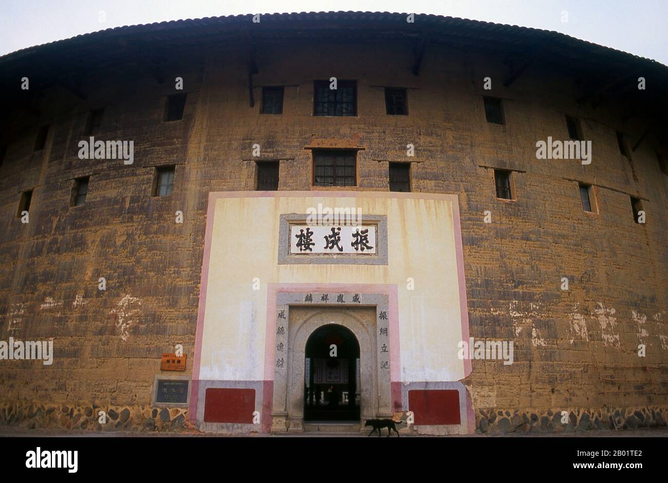 China: The only entrance into the Zhenchang Lou Hakka Tower near Hukeng, Yongding County, Fujian Province.  The Hakka (Kejia in Mandarin; literally 'guest people') are Han Chinese who speak the Hakka language. Their distinctive earthen houses or tulou can be found in the borderland counties where Guangdong, Jiangxi and Fujian provinces meet.  Communal entities, tulou are fortified against marauding bandits and generally made of compacted earth, bamboo, wood and stone. They contain many rooms on several storeys, so that several families can live together. Stock Photo