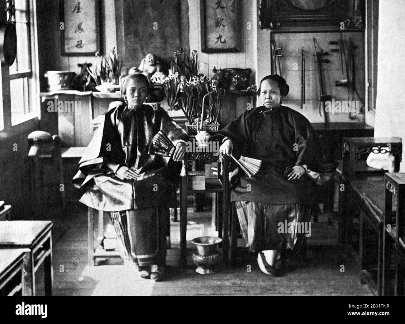 USA: Two well-to-do ethnic Chinese women in a restaurant, musical instruments hanging on wall to right. San Francisco Chinatown, c. 1900.  San Francisco's Chinatown was the port of entry for early Hoisanese and Zhongshanese Chinese immigrants from the Guangdong province of southern China from the 1850s to the 1900s. The area was the one geographical region deeded by the city government and private property owners which allowed Chinese persons to inherit and inhabit dwellings within the city. Stock Photo