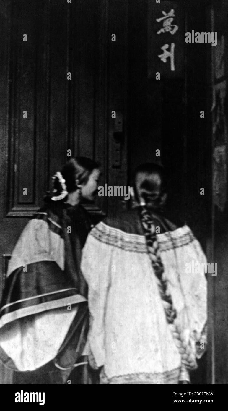 USA: Two ethnic Chinese girls chatting at a doorway, San Francisco Chinatown, c. 1900.  San Francisco's Chinatown was the port of entry for early Hoisanese and Zhongshanese Chinese immigrants from the Guangdong province of southern China from the 1850s to the 1900s. The area was the one geographical region deeded by the city government and private property owners which allowed Chinese persons to inherit and inhabit dwellings within the city.  The majority of these Chinese shopkeepers, restaurant owner, and hired workers in San Francisco Chinatown were predominantly Hoisanese and male. Stock Photo