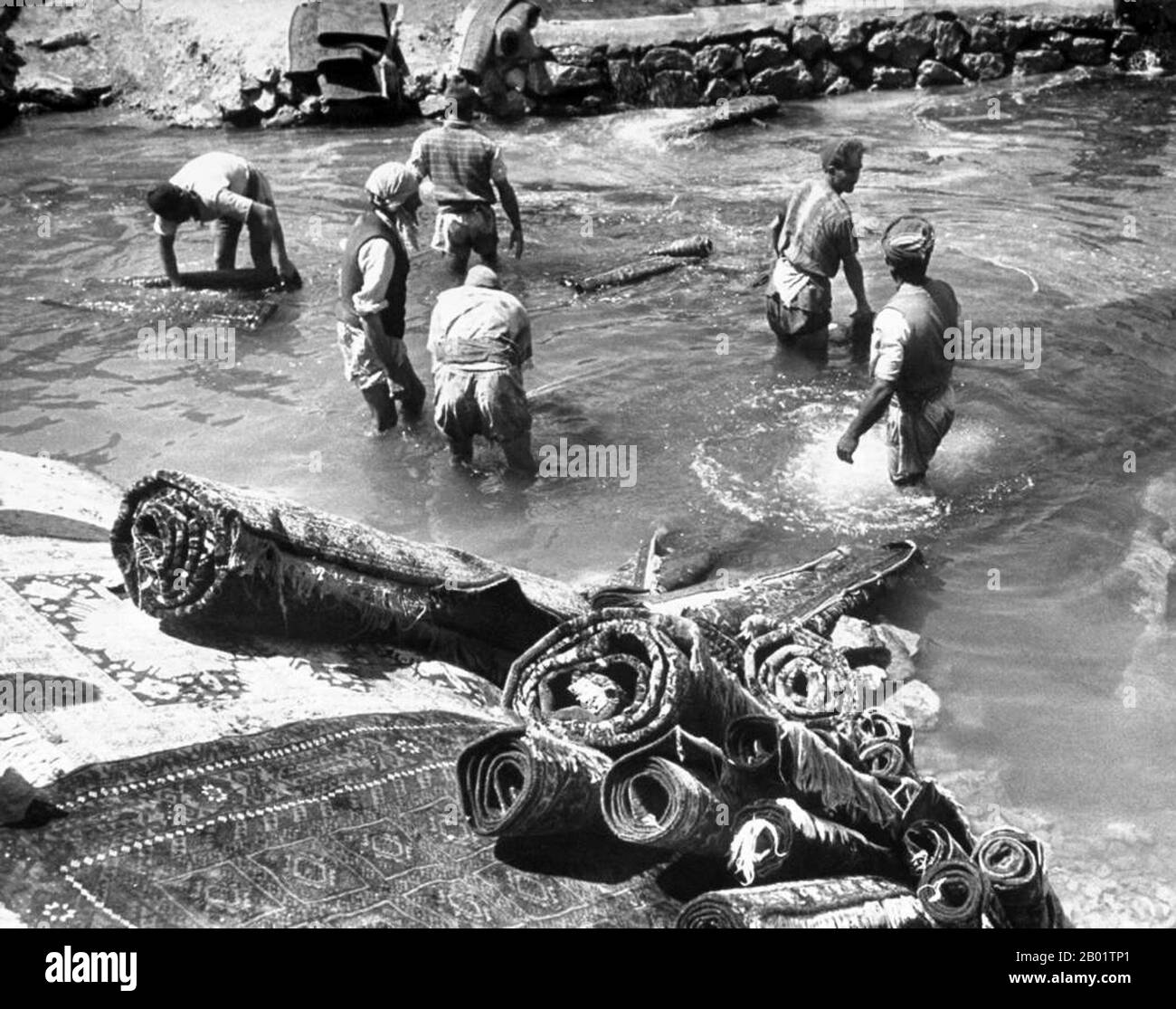 Iran/Persia: A group of men washing Persian rugs in a river, Tabriz, northern Iran, c. 1930.  An authentic oriental rug is a handmade carpet that is either knotted with pile or woven without pile.  By definition - Oriental rugs are rugs that come from the orient. The simple definition of the term would be - rugs that come from (were made in) an Asian Country such as: China and Vietnam in the east to Turkey, Maghreb countries, Cyprus and Iran in the west and the Caucasus in the north to India in the south. Stock Photo