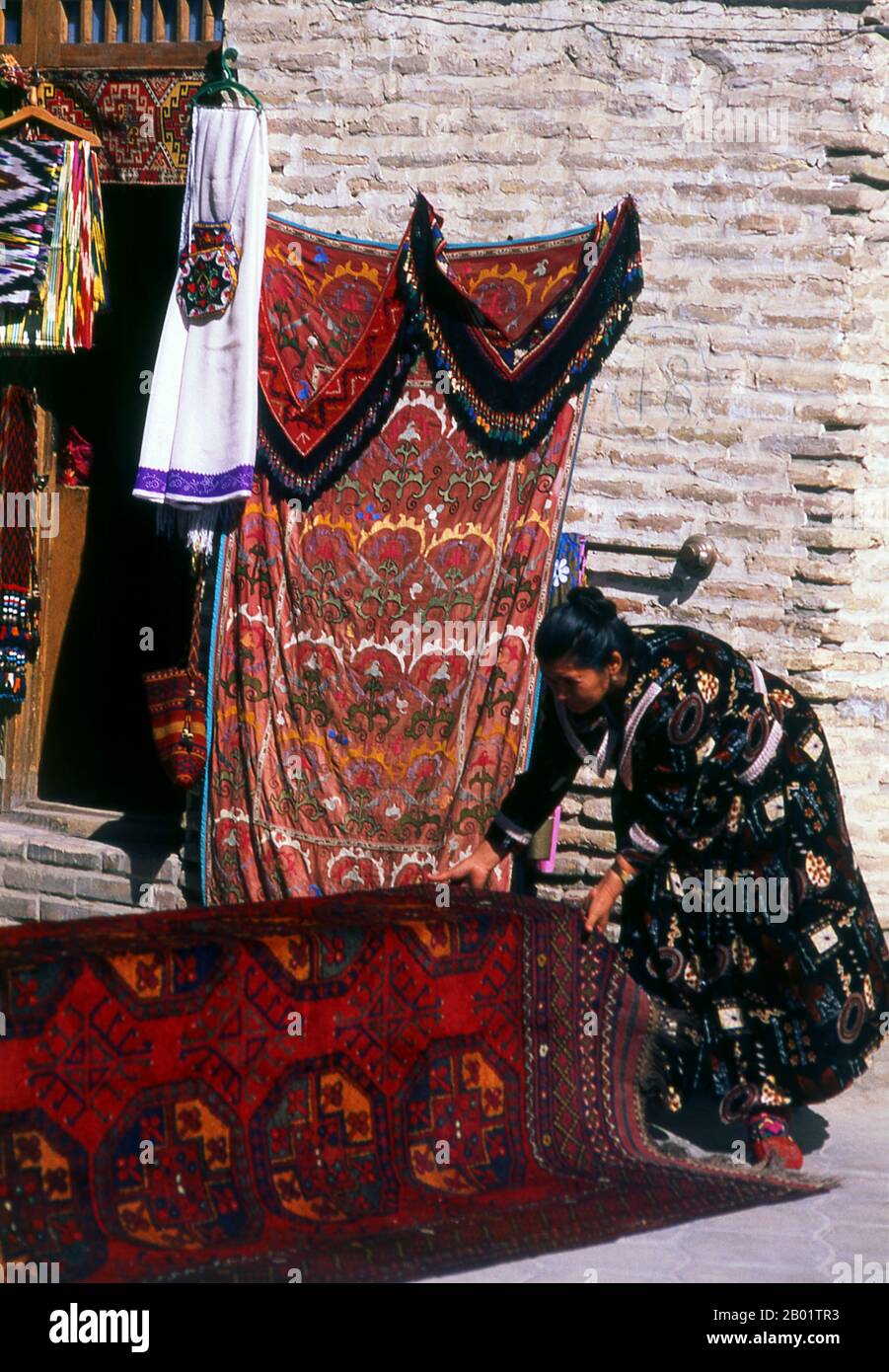 Uzbekistan: Carpet seller at the Taqi Telpak Furushon (the cap makers) Bazaar, Bukhara.  Bukhara was founded in 500 BCE in the area now called the Ark. However, the Bukhara oasis had been inhabited long before.  The city has been one of the main centres of Persian civilisation from its early days in 6th century BCE. From the 6th century CE, Turkic speakers gradually moved in.  Bukhara's architecture and archaeological sites form one of the pillars of Central Asian history and art. The region of Bukhara was for a long period a part of the Persian Empire. Stock Photo