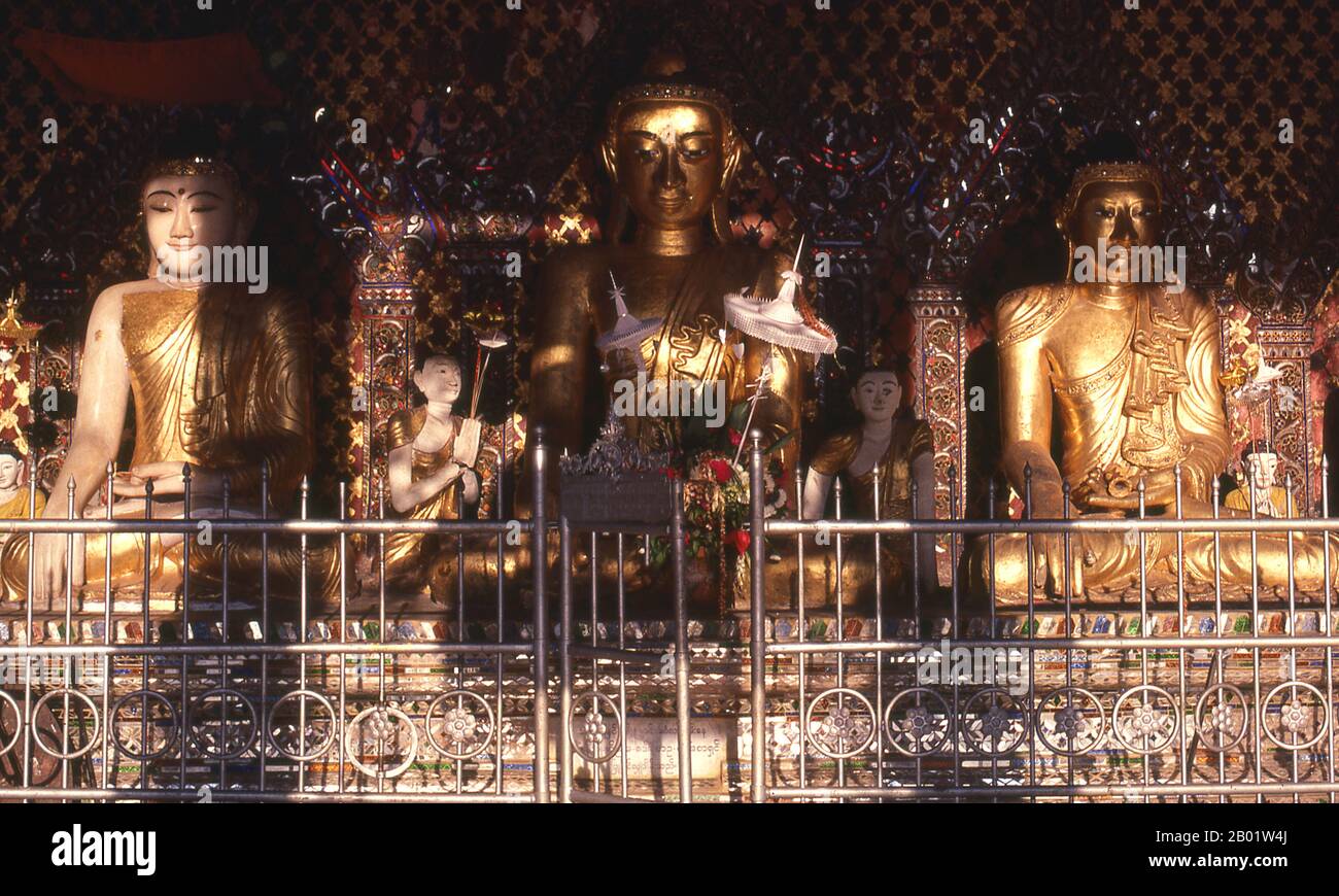Burma/Myanmar: Buddha figures within a small shrine in the Shwedagon Pagoda complex, Yangon (Rangoon).  The golden stupa of the Shwedagon Pagoda rises almost 100 m (330ft) above its setting on Singuttara Hill and is plated with 8,688 solid-gold slabs. This central stupa is surrounded by more than 100 other buildings, including smaller stupas and pavilions.  The pagoda was already well established when Bagan dominated Burma in the 11th century. Queen Shinsawbu, who ruled in the 15th century, is believed to have given the pagoda its present shape. Stock Photo