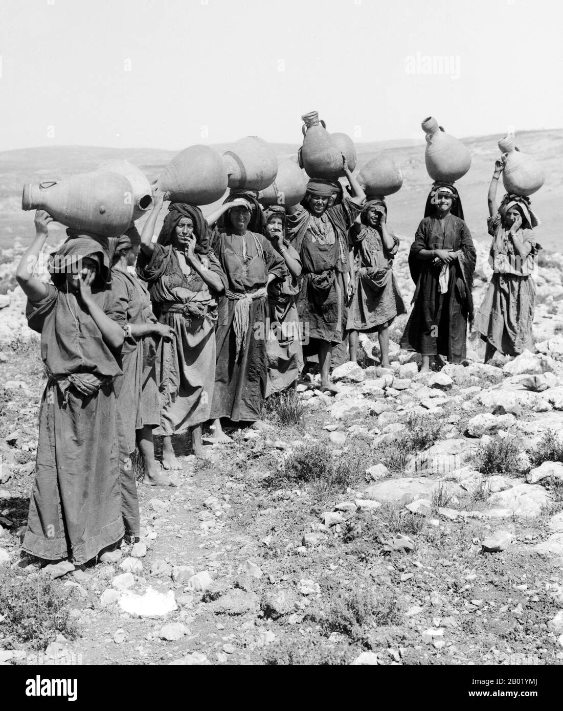 Palestine: A line of Palestinian women posing with water pots on their heads, Safed (modern-day Tsefat), c. 1900-1920.  Palestine is a name given to the geographic region between the Mediterranean Sea and the Jordan River. The region is also known as the Land of Israel, the Holy Land and the Southern Levant.  In 1832 Palestine was conquered by Muhammad Ali's Egypt, but in 1840 Britain intervened and returned control of the Levant to the Ottomans in return for further capitulations. The end of the 19th century saw the beginning of Zionist immigration and the Revival of the Hebrew language. Stock Photo