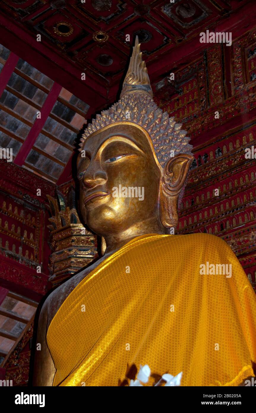 Thailand: Buddha figure in the old viharn, Wat Hang Dong, Chiang Mai, northern Thailand.  Wat Hang Dong is a typical example of traditional Lan Na temple architecture. The old viharn at this temple is a little more elaborate than its counterpart at nearby Wat Ton Kwen, but is essentially similar in shape, style and appearance. Also dark and intimate, with a low, sweeping, three-tiered roof, the viharn shelters a collection of Buddha images, at least two of which - to the right and left of the main Buddha image - are distinctively Lao in style and yet somehow strangely primitive. Stock Photo