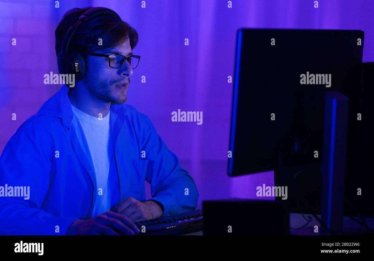 Programmer In Eyeglasses Coding On PC At Home, Low Light Stock Photo