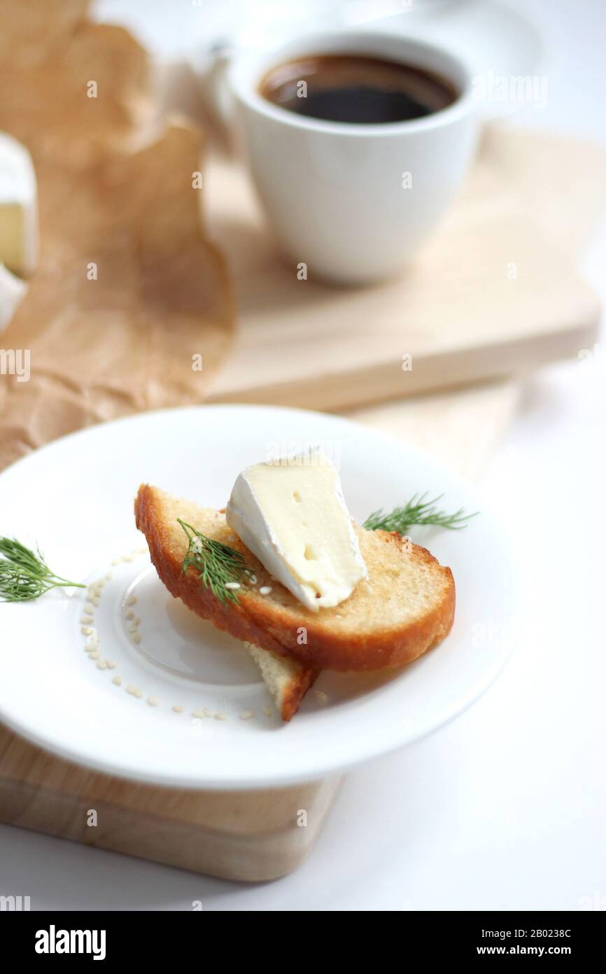 Delicious French Cheese Camembert on fresh Toast  with a Cup of freshly brewed Coffee. Food styling. Traditional French Product. Breakfast, Brunch tab Stock Photo
