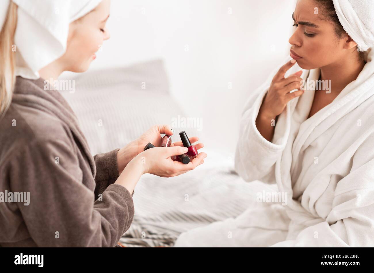 Thoughtful black girl in bathrobe choosing nail polisher color Stock Photo Alamy
