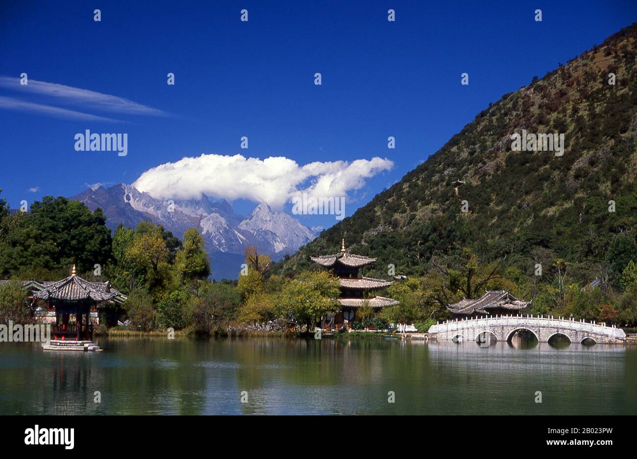China: Jade Dragon Snow Mountain seen from Black Dragon Pool Park (H��il��ngt��n), Lijiang, Yunnan Province.  Black Dragon Pool, built in 1737 during the Qing period, is located slightly to the north of Lijiang's Old Town and offers one of China's most spectacular views.  Jade Dragon Snow Mountain is a small mountain range near Lijiang, in Yunnan province of southwestern China. Its highest peak is named Shanzidou (5,596 m or 18,360 ft). The far side of the mountain forms one side of Tiger Leaping Gorge (Hutiao Xia). Stock Photo
